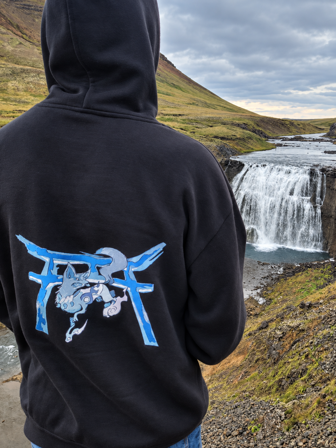 Sweat MENSHi avec motif bleu brodé dans le dos, porté devant une cascade